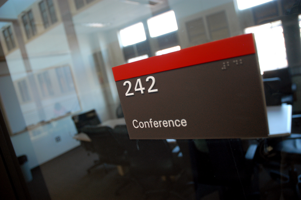 A sign outside of a conference room shows the conference number