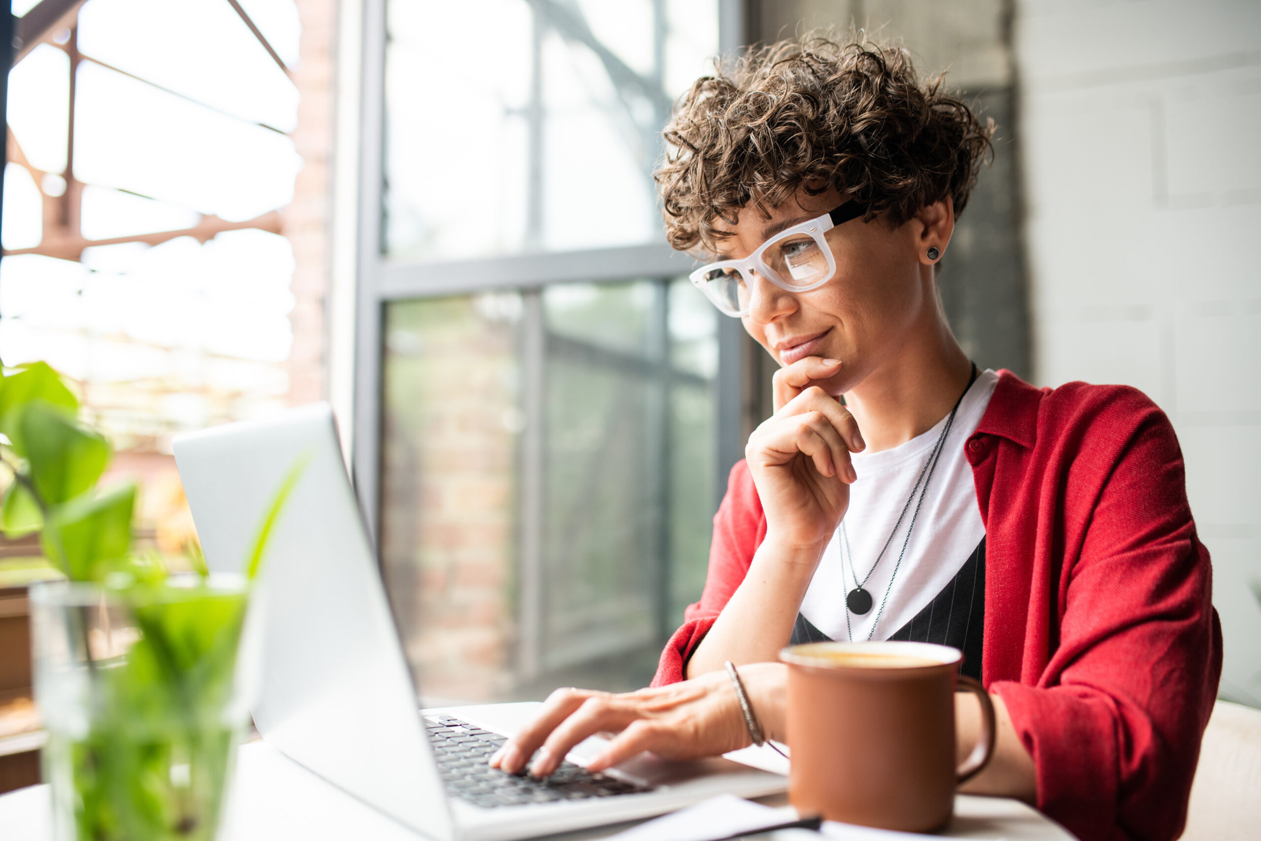 A woman sits outside typing on a laptop