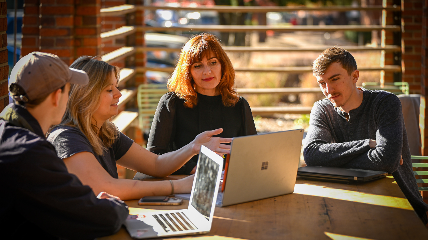 Four people chat and look at a laptop