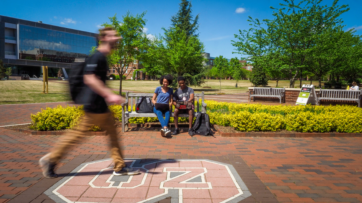 Students sit and walk on Centennial Campus on a sunny summer day.