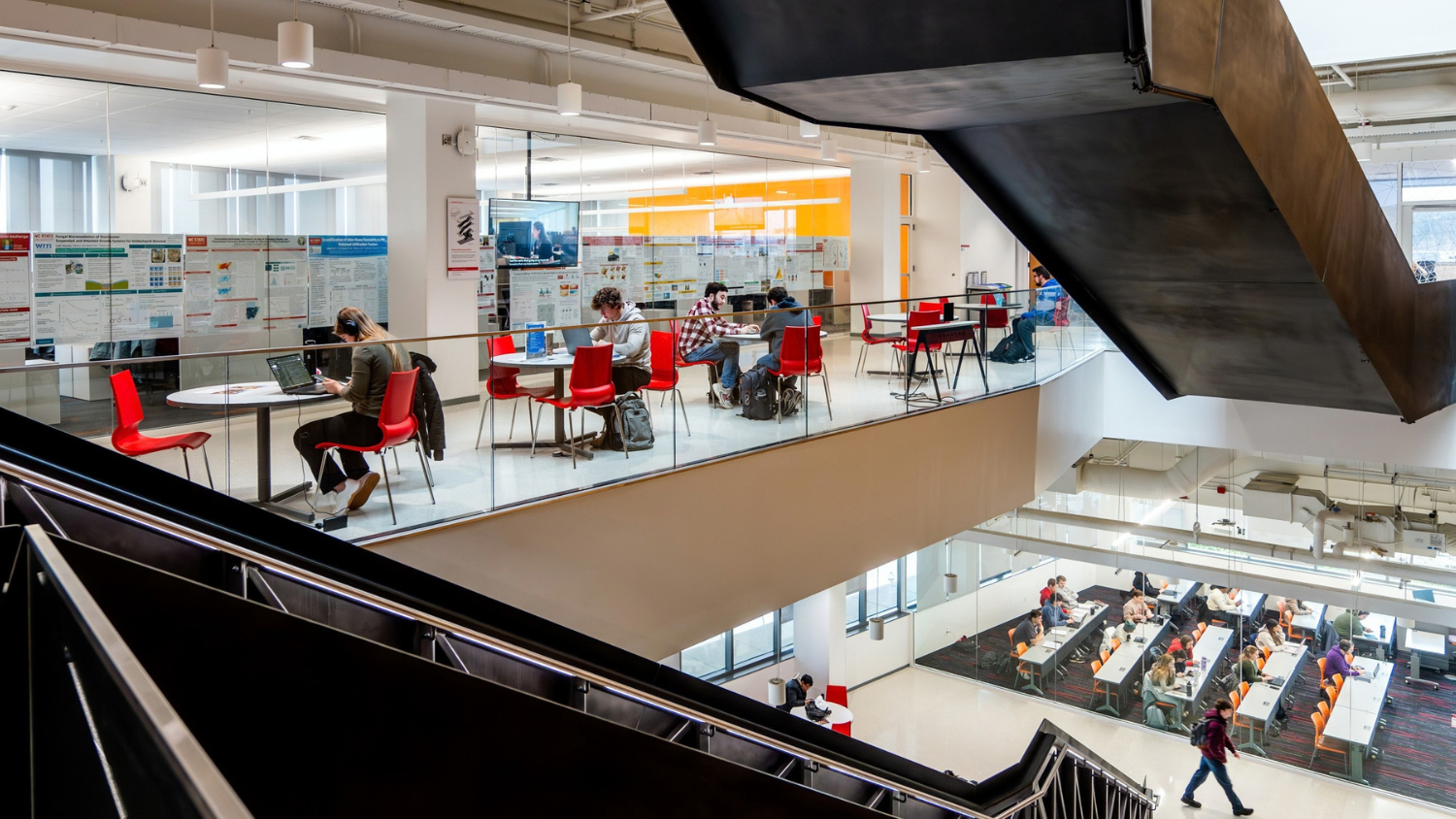 Students sit at small tables and in a classroom in Fitts-Woolard surrounded by large staircases
